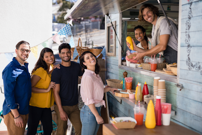 Smiling waiter giving order to customers at counter in food truck