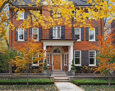 large brick house surrounded by trees with fall colors