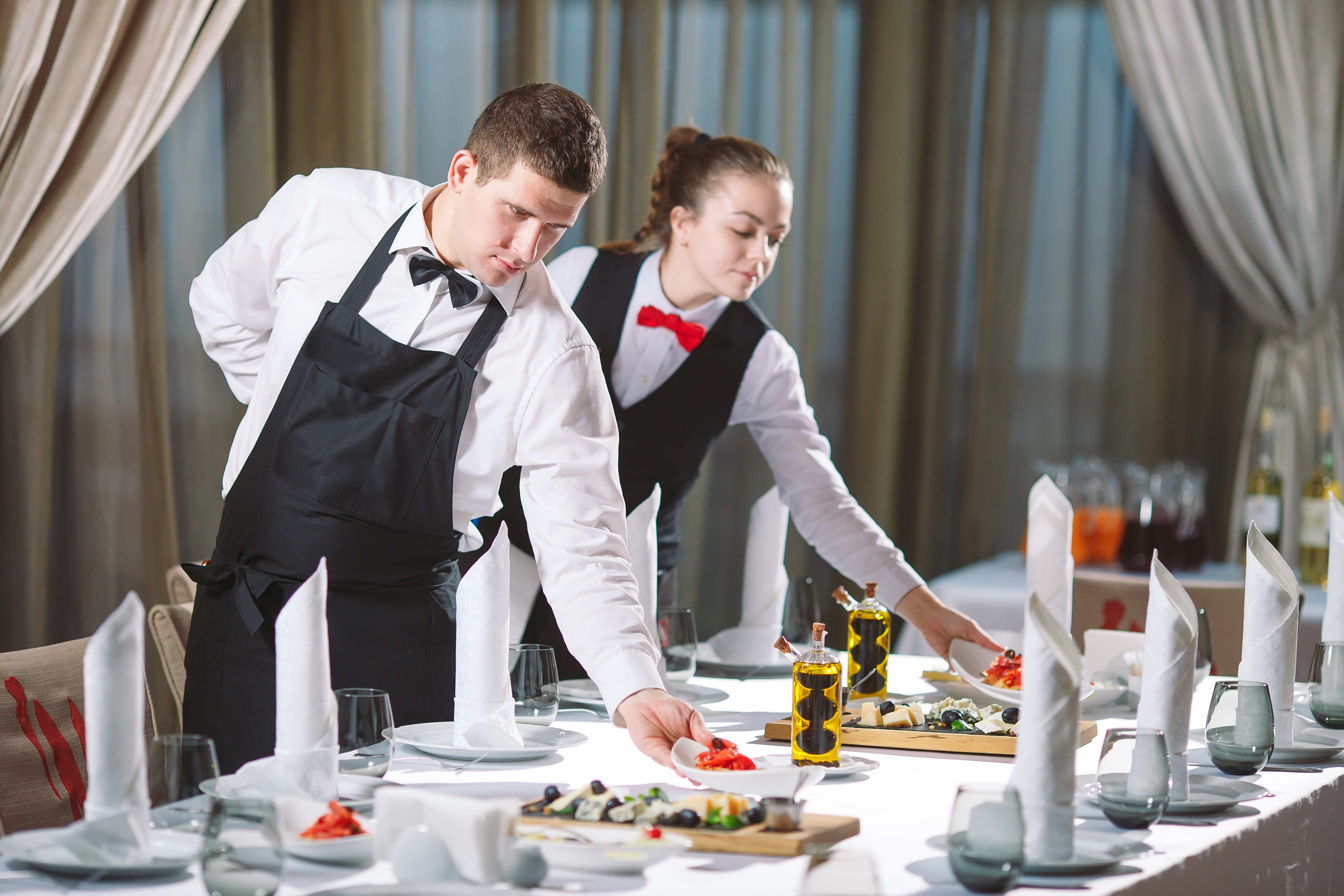 Waiters serving table in the restaurant preparing to receive guests.