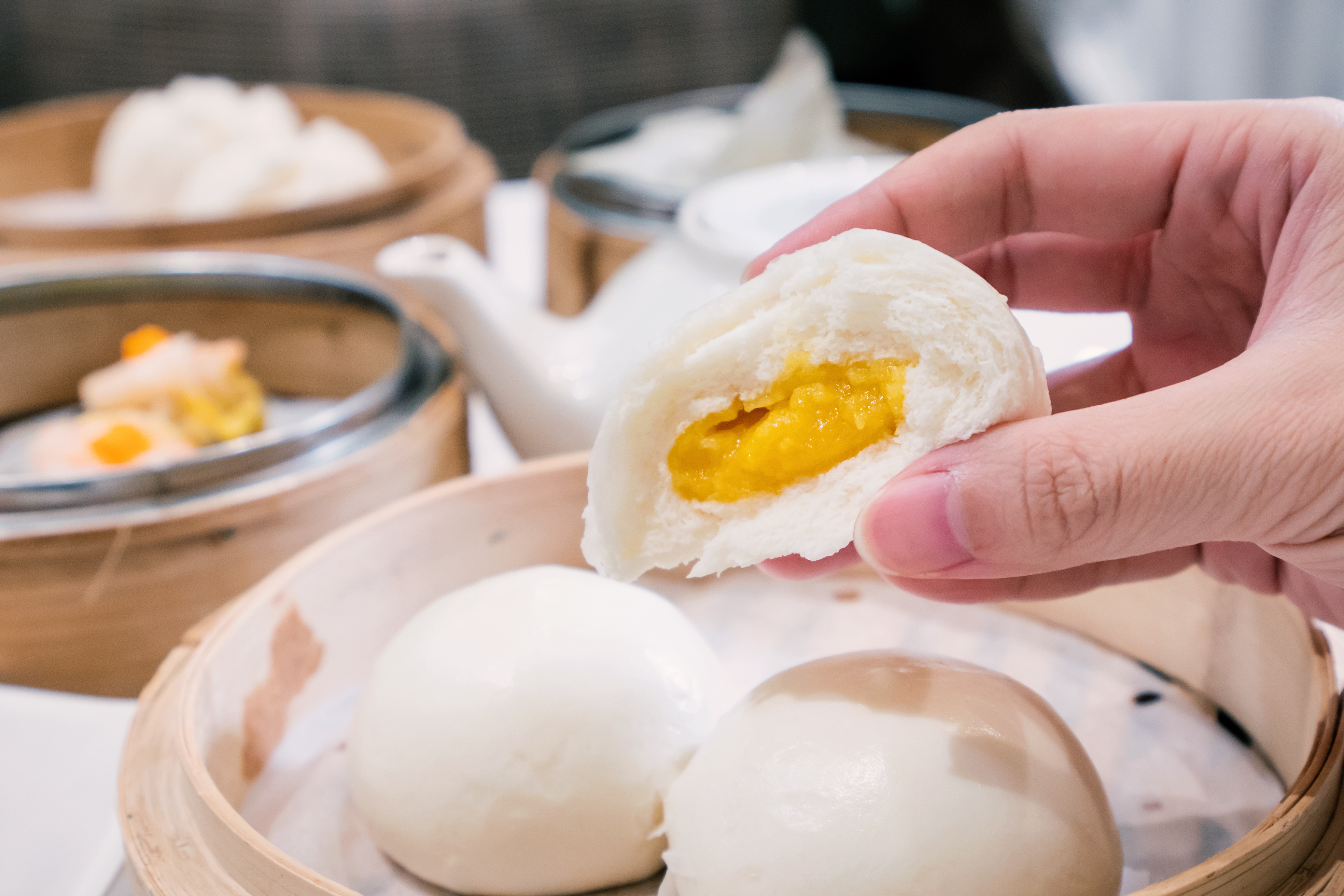 Delicious dim sum, famous cantonese food in asia, fresh and hot salted creamy custard buns in bamboo steamer in hong kong yumcha restaurant, close up