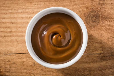 Traditional Latin American dulce de leche or manjar on wooden background. Top view