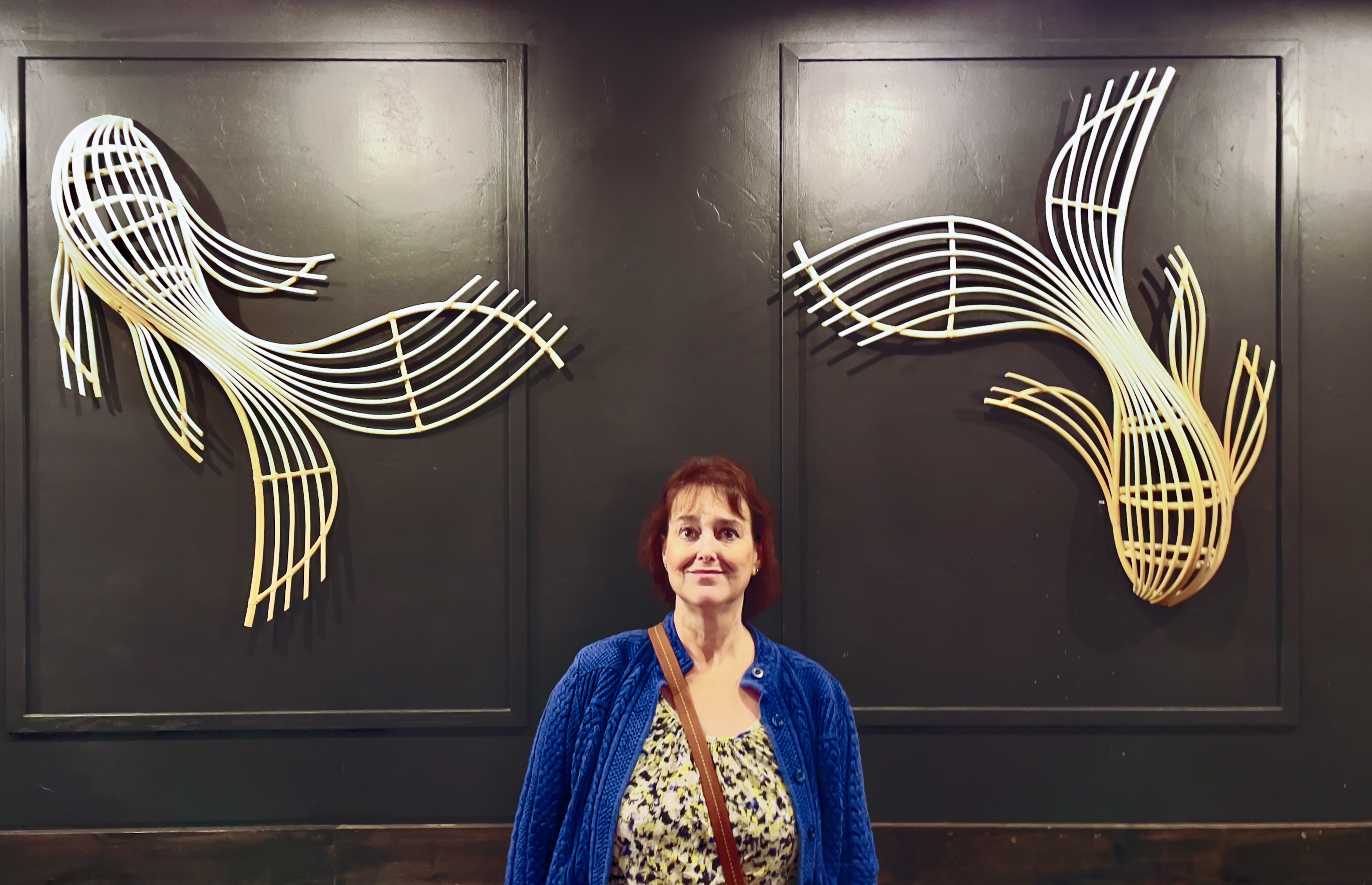 Kathy poses in front of rattan cane koi sculptures at Baan Thai.