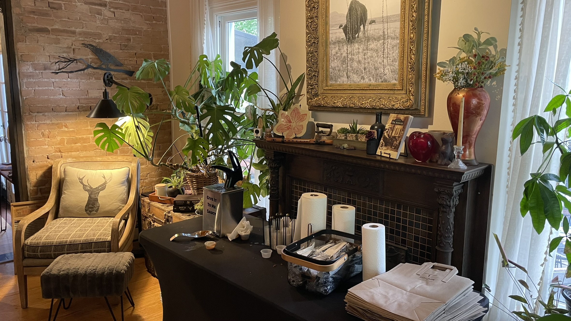 The self-service station at Blatch's Vegan BBQ, providing plastic utensils, paper bags, and paper towels, with plastic cups and lids to accompany the dispenser of Blatch’s own barbecue sauce