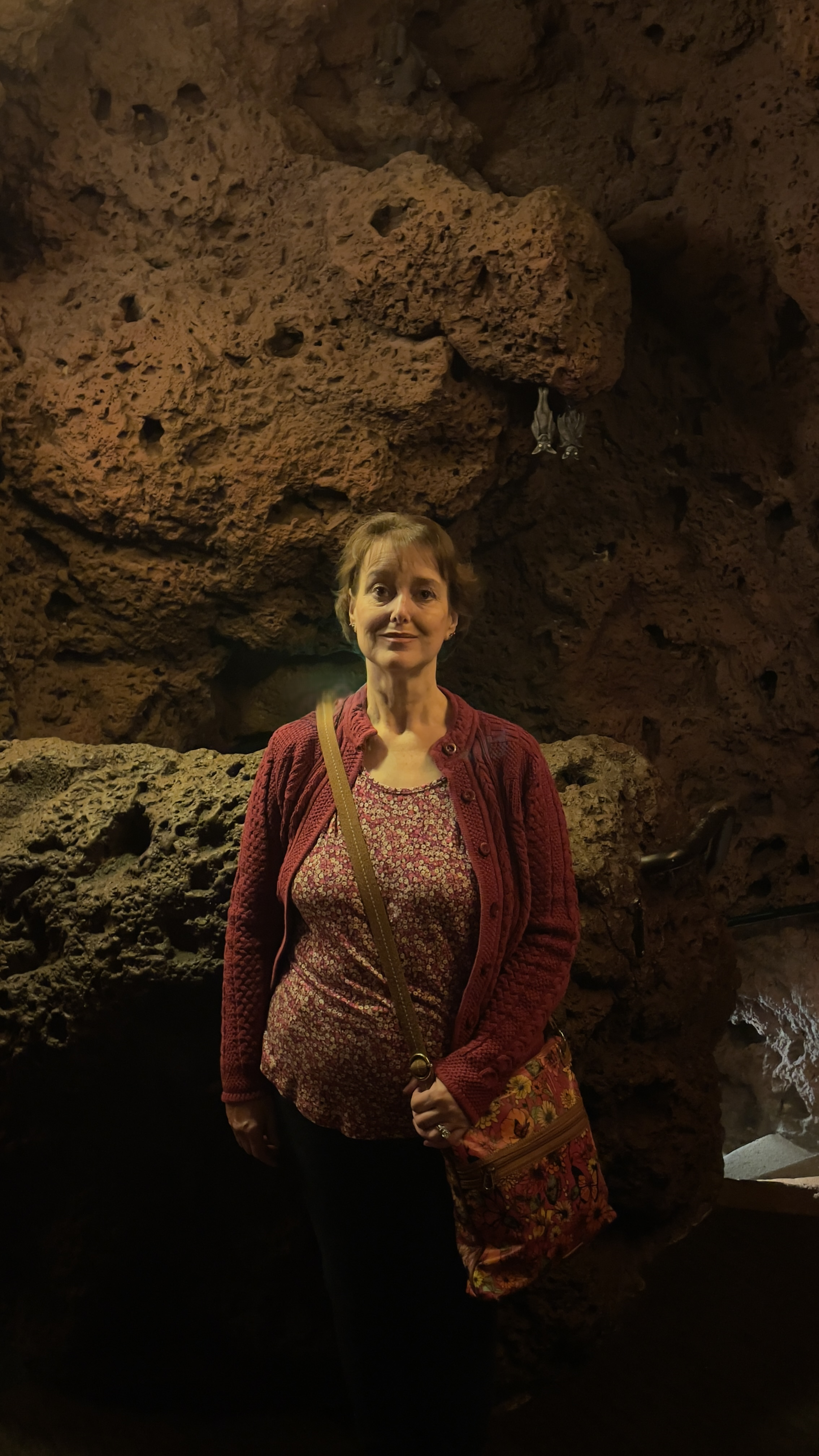 Kathy poses with bats hanging in a cave at Casa Bonita.