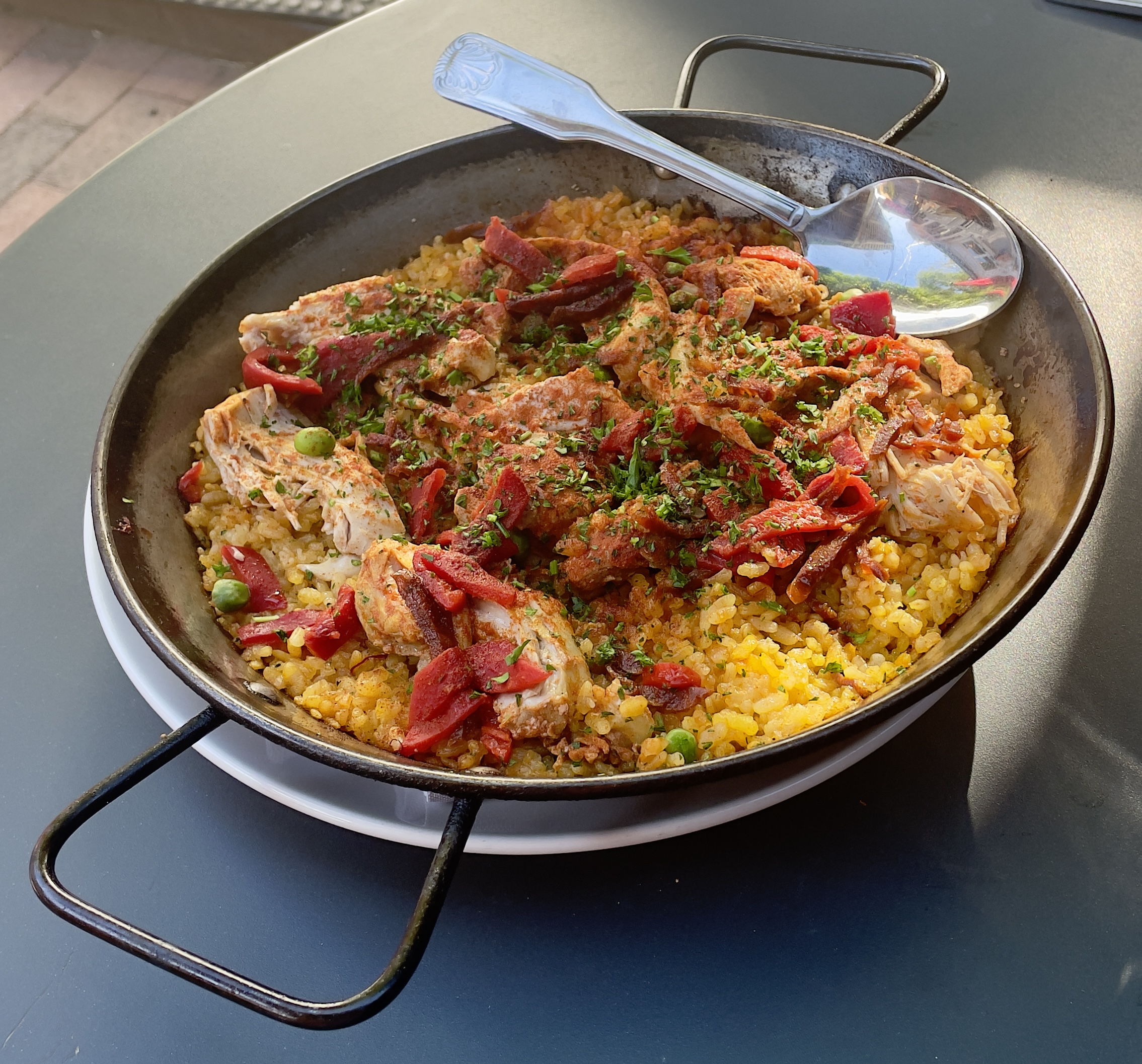 The Paella de Valenciana plate at Finca: classic Spanish rice dish, chicken thighs, chorizo, piquillo pepper, peas.
