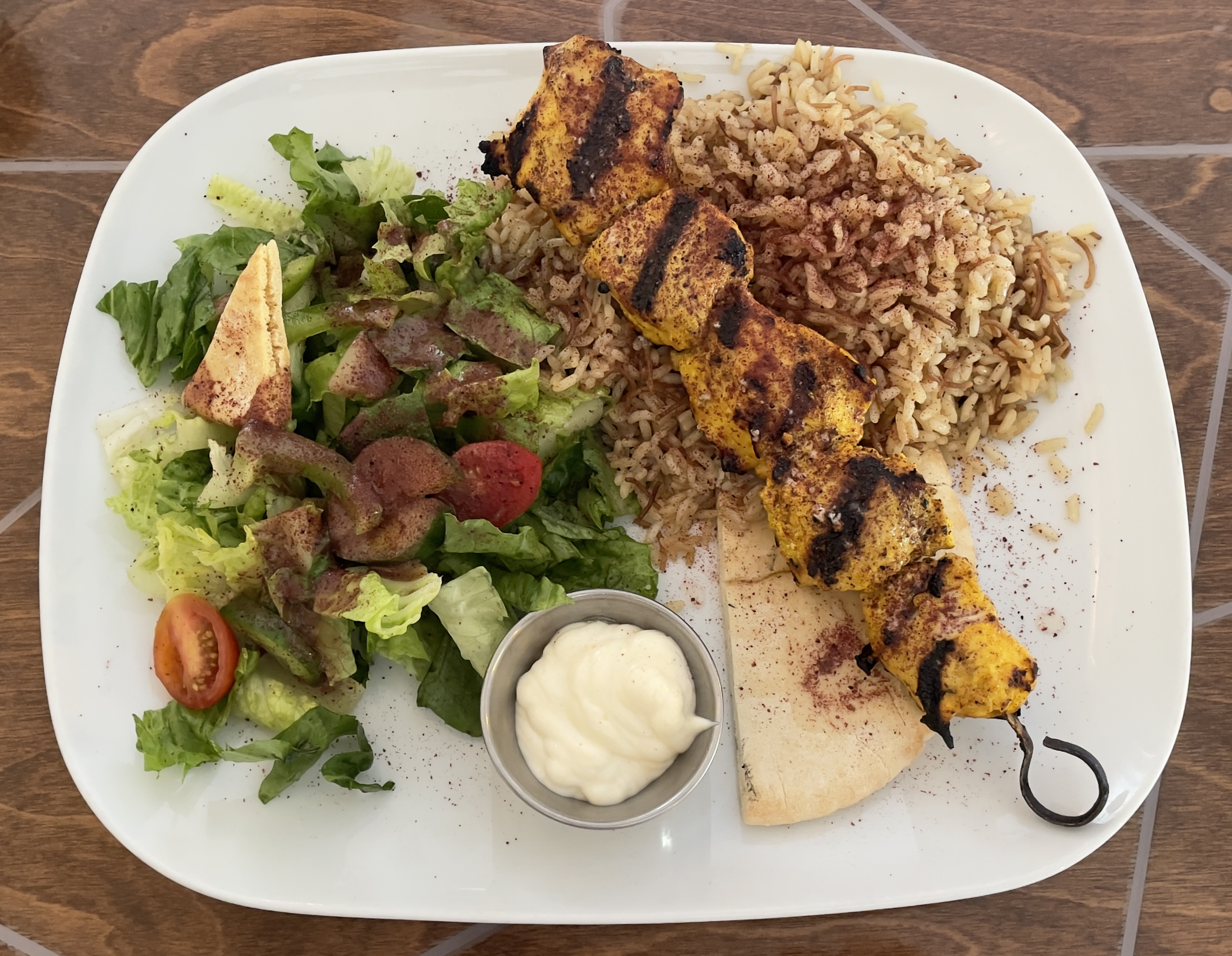 Chicken Kabob Platter at Layla Mediterranean Grill and Mezze.  Tender cuts of chicken, marinated in yogurt and exotic spices.  Charbroiled and served with house garlic “toum” aioli.  Served with Lebanese vermicelli rice, warm pita, and a house Fattoush salad.