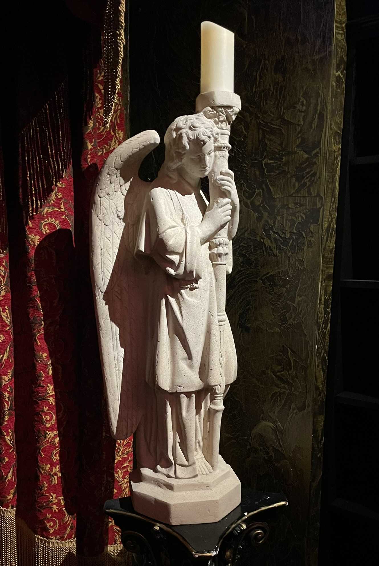 A statue of an angel holds a large candle at Mystique Dining at Gardner Village