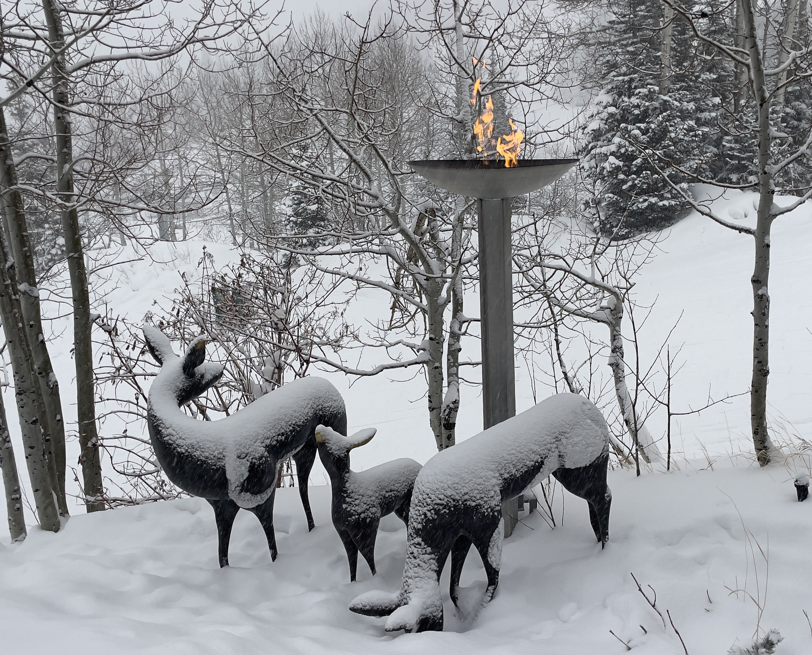 Snow falls on three deer statues in front of a live flame feature just outside the Troll Hallen Lounge.